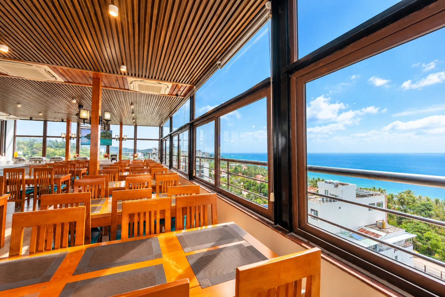 Restaurant with wooden tables and chairs beside sea-view windows at Nam Chau Stellar